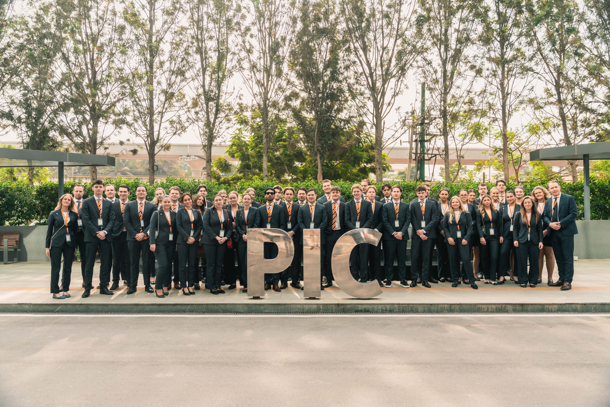 Groepsfoto van hospitality studenten in pak voor het Philips Innovation Campus-logo, symbool voor ambitie en toekomstgericht onderwijs bij EuroCollege.